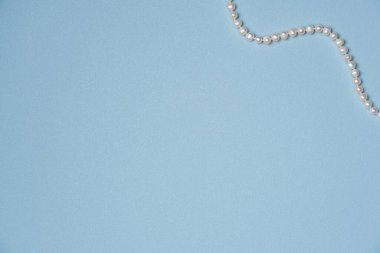 Mavi arkaplan ve inci kolye. Düz yerde, üst tarafta. Boşluğu kopyala