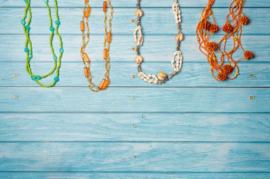 Farklı plaj kolyeleri. Mavi ahşap arka planda yaz plajı mücevherleri. Düz yatış, üst görünüm