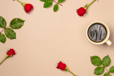 Kırmızı gül çerçevesi ve bej arka planda bir kupa kahve. Düz yerde, üst tarafta. Boşluğu kopyala