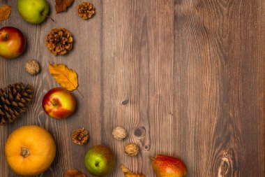 Sonbahar hasadı. Balkabağı, armut, elma, fındık, kozalak ve tahta arka planda yapraklar. Boşluğu kopyala, üst görünüm