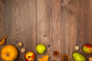 Sonbahar hasadı. Balkabağı, armut, elma, fındık, kozalak ve tahta arka planda yapraklar. Boşluğu kopyala, üst görünüm