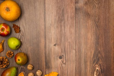 Sonbahar hasadı. Balkabağı, armut, elma, fındık, kozalak ve tahta arka planda yapraklar. Boşluğu kopyala, üst görünüm