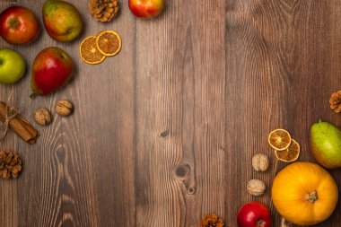 Sonbahar hasadı. Balkabağı, armut, elma, fındık, kozalak ve ahşap zemin üzerinde tarçın. Boşluğu kopyala, üst görünüm