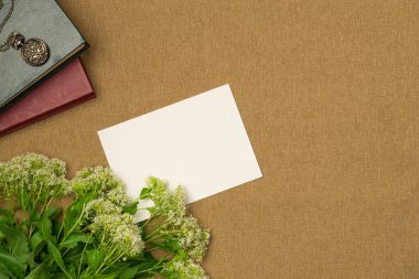 Kağıt boş çarşaf, kitaplar, çiçek ve madalyon yukarıdan kumaş arka planda. Metin için boşluk