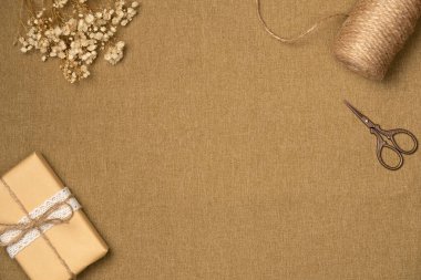 Kumaş arka plan, tel, makas, hediye kutusu ve yukarıdan çiçekler. Eski tarz. Boşluğu kopyala