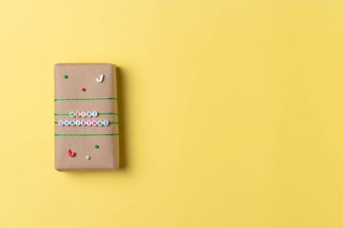 Sarı arka planda Noel hediyesi kutusu. Düz yerde, üst tarafta. Boşluğu kopyala