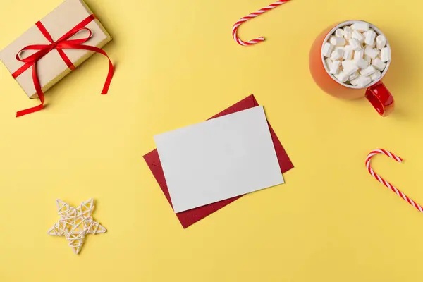 Hediye kutusu, lokum ve sarı arka planda süslemeleri olan boş beyaz kağıt liste. Noel konsepti. Düz yatış, üst görünüm.