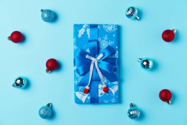 Mavi arka planda süslemeleri olan Noel hediyesi kutusu. Düz yatış, üst görünüm