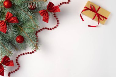 Süslemeleri olan bir Noel ağacı dalı ve beyaz arka planda hediye kutusu. Düz yerde, üst tarafta. Boşluğu kopyala