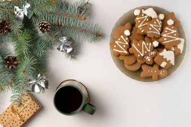 Süslü Noel ağacı dalı, zencefilli ekmek tabağı ve beyaz arka planda hediye kutusu. Düz yatış, üst görünüm.