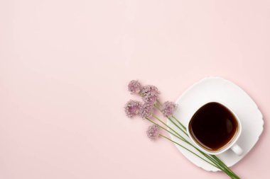 Pembe arka planda çiçekli bir fincan kahve. Düz yerde, üst tarafta. Boşluğu kopyala