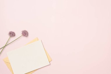 Pembe arka planda çiçekler olan kağıt boş bir sayfa. Tebrik kartı. Mesaj için yer var. Düz yatış, üst görünüm.