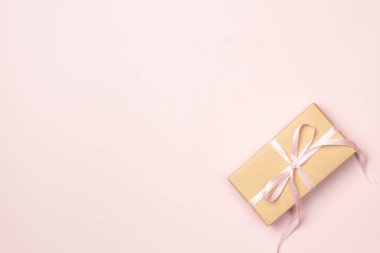 Pembe arka planda bir hediye kutusu. Düz yerde, üst tarafta. Boşluğu kopyala