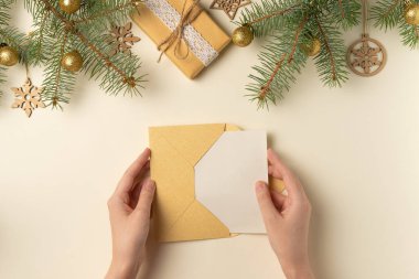 Bej arka planda kadın ellerinde boş bir kartın olduğu zarf. Noel konsepti. Düz yatış, üst görünüm