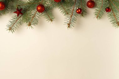 Noel ağacı dalları ve kırmızı oyuncaklarla bej arka plan. Düz yerde, üst tarafta. Boşluğu kopyala