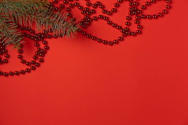 Boncuklu ve ladin dallı kırmızı bir Noel arkaplanı. Düz yerde, üst tarafta. Boşluğu kopyala