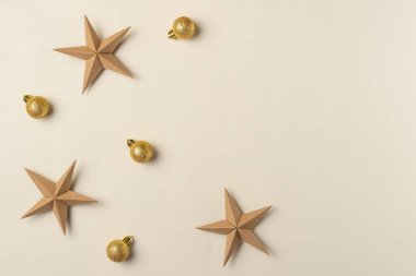 Altın küreli ve yıldızlı Noel bej arka planı. Düz yerde, üst tarafta. Boşluğu kopyala