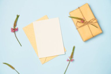 Yukarıdan mavi arka planda çiçek ve hediye kutusu olan kâğıt boş bir sayfa. Tebrik kartı. Metin için boşluk