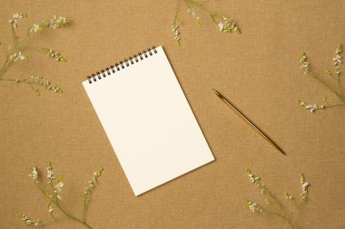 Kumaş arka planında çiçek çerçevesi olan boş bir defter. Düz yerde, üst tarafta. Metin için boşluk