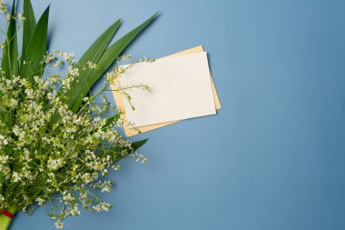 Mavi arka planda bir buket çiçekli kağıt boş çarşaf. Düz yatış, üst görünüm.