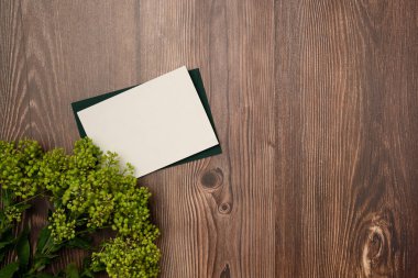 Tahta zemin üzerinde çiçekler olan kağıt boş çarşaf. Düz yatış, üst görünüm.