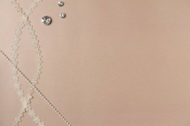 Bej arka planda aksesuarlar dikiyorum. Elmas, dekor ve düğmeler. Düz yerde, üst tarafta. Boşluğu kopyala