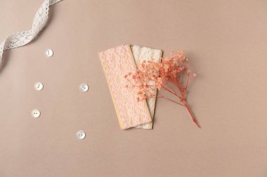 Bej arka planda çiçekli bant ve düğmeler. Aksesuar dikiyorum. Düz yatış, üst görünüm.