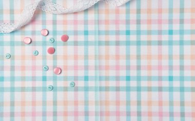 Kumaş arka planda düğmeler ve kurdeleler. Düz yerde, üst tarafta. Boşluğu kopyala