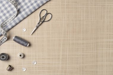 Masaya aksesuar dikiyorum. Kumaş, iplik, düğmeler, makas, yüksük, bobbin. Düz yerde, üst tarafta. Boşluğu kopyala