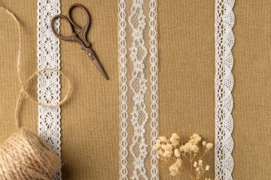 Kumaş zemin üzerinde iplik ve makas olan farklı klasik kurdeleler. Düz yatış, üst görünüm.