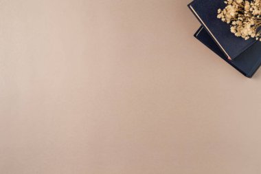 Yukarıdan bej arka planda çiçekli kitaplar. Düz yerde, üst tarafta. Boşluğu kopyala