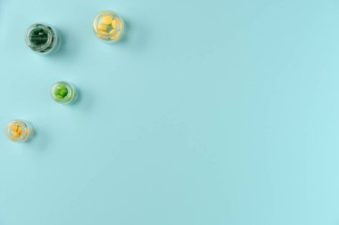 Tabletler mavi arka planda cam kavanozlarda. Düz yerde, üst tarafta. Boşluğu kopyala