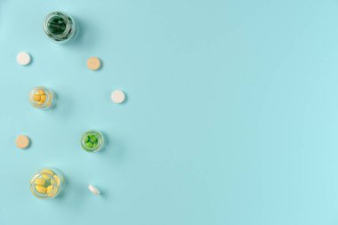 Tabletler mavi arka planda cam kavanozlarda. Düz yerde, üst tarafta. Boşluğu kopyala