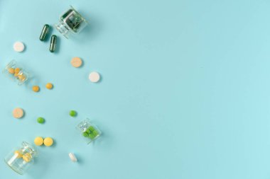 Tabletler mavi arka planda cam kavanozlarda. Düz yerde, üst tarafta. Boşluğu kopyala