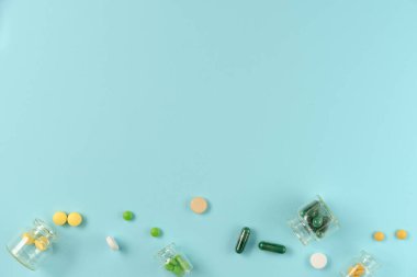 Tabletler mavi arka planda cam kavanozlarda. Düz yerde, üst tarafta. Boşluğu kopyala