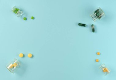 Mavi arka planda cam kavanozlardaki tabletlerin çerçevesi. Düz yerde, üst tarafta. Boşluğu kopyala