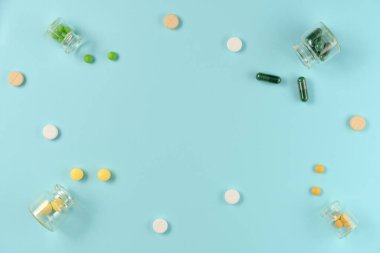 Mavi arka planda cam kavanozlardaki tabletlerin çerçevesi. Düz yerde, üst tarafta. Boşluğu kopyala