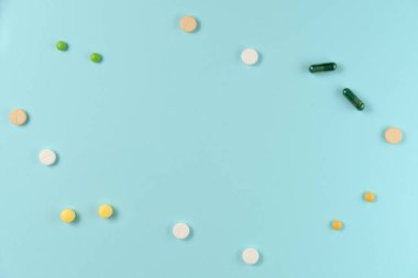 Mavi arka planda bir sürü farklı hapın çerçevesi. Düz yatış, üst görünüm.