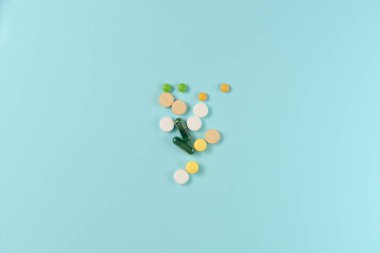 Mavi arka planda bir sürü farklı hap var. Düz yatış, üst görünüm.