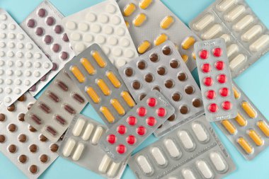 Mavi arka planda farklı haplarla su toplamış. Düz yatış, üst görünüm.