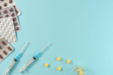 Mavi arka planda farklı haplar ve şırıngalarla su toplamış. Düz yerde, üst tarafta. Boşluğu kopyala