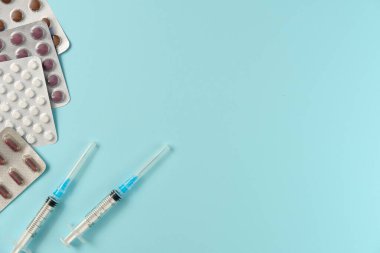 Mavi arka planda farklı haplar ve şırıngalarla su toplamış. Düz yerde, üst tarafta. Boşluğu kopyala