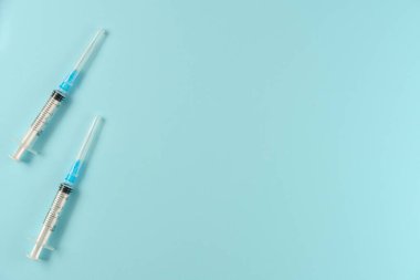 Mavi arka planda iki şırınga. Düz yerde, üst tarafta. Boşluğu kopyala