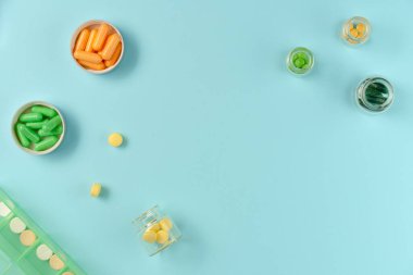 Kavanozlardaki tabletler ve mavi arka plandaki ilaç kutusu. Düz yerde, üst tarafta. Boşluğu kopyala