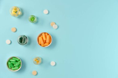 Tabletler mavi arka planda cam kavanozlarda. Düz yerde, üst tarafta. Boşluğu kopyala