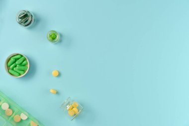 Kavanozlardaki tabletler ve mavi arka plandaki ilaç kutusu. Düz yerde, üst tarafta. Boşluğu kopyala