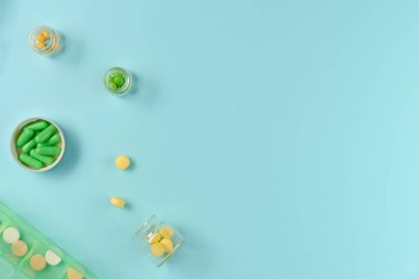 Kavanozlardaki tabletler ve mavi arka plandaki ilaç kutusu. Düz yerde, üst tarafta. Boşluğu kopyala