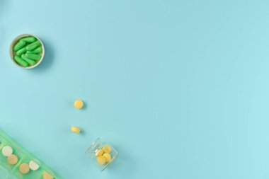 Kavanozlardaki tabletler ve mavi arka plandaki ilaç kutusu. Düz yerde, üst tarafta. Boşluğu kopyala