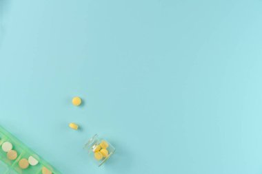 Kavanozlardaki tabletler ve mavi arka plandaki ilaç kutusu. Düz yerde, üst tarafta. Boşluğu kopyala