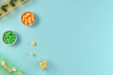 Kavanozlardaki tabletler ve mavi arka plandaki ilaç kutusu. Düz yerde, üst tarafta. Boşluğu kopyala